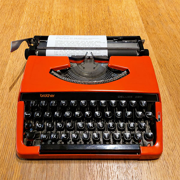 photo of a red Brother typewriter with some paper loaded
